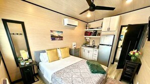 A compact bedroom with a bed, bedside table, and a small desk.