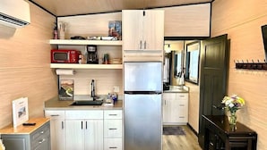 A compact kitchen with a refrigerator, microwave, and sink. There are cabinets and a small countertop.