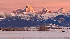 A mountainous landscape with snow-covered peaks and a clear sky.
