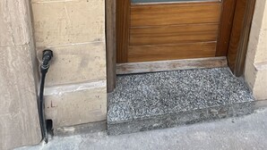 Une porte en bois avec une poignée, une fente pour le courrier et trois numéros de maison au-dessus.