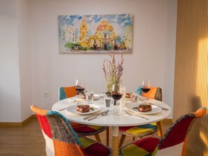 Una mesa de comedor con sillas, platos con comida, copas de vino y un jarrón con flores.