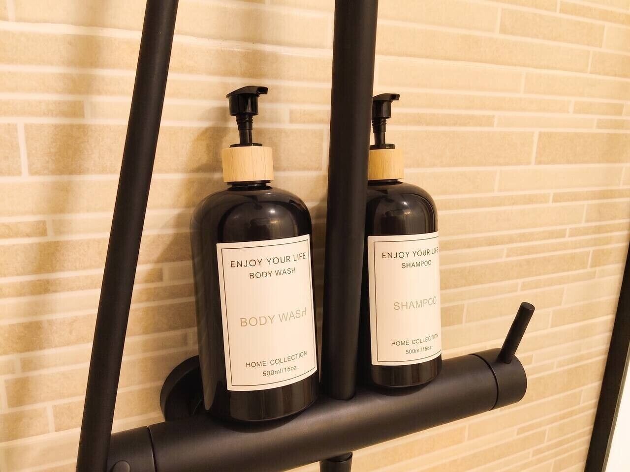 Two bottles of body wash and shampoo on a black soap dispenser.