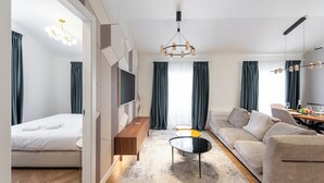 Una habitación de hotel moderna con cama, sofá, televisión y un comedor.