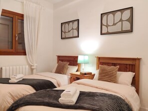 Een hotelkamer met twee bedden, een nachtkastje met een lamp en kunstwerken aan de muren.