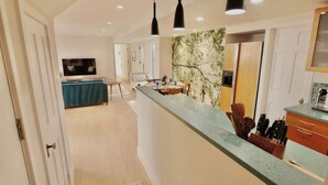 Una cucina moderna con un'isola centrale, un'area pranzo con tavolo e sedie e un soggiorno con televisione.