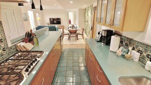 Una cucina moderna con isola centrale, zona pranzo con tavolo e sedie, e pensili in legno.
