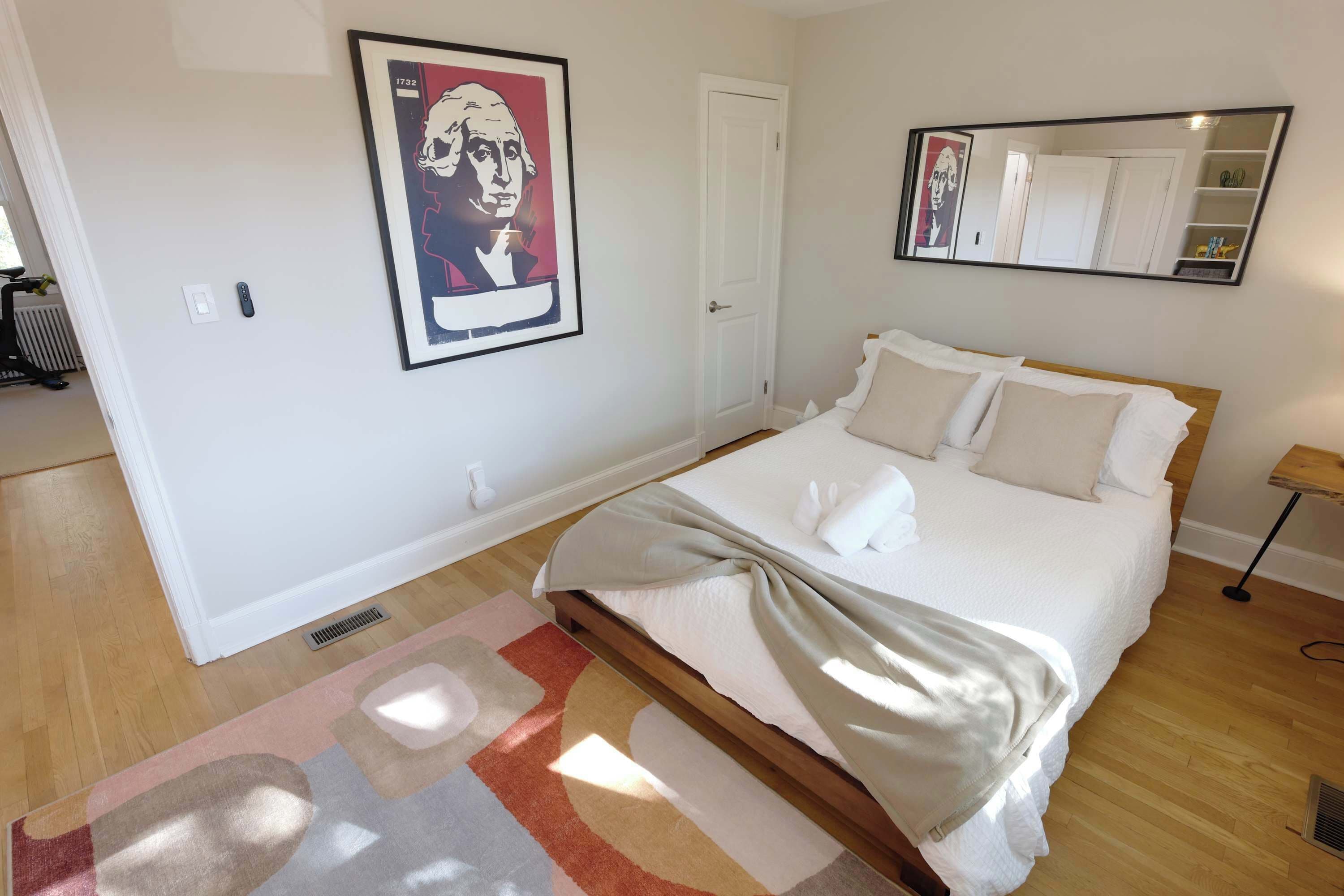 Quarto com uma cama, um espelho grande, um quadro na parede e um radiador.