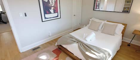 A bedroom with a bed, a large mirror, a framed picture on the wall, and a radiator.