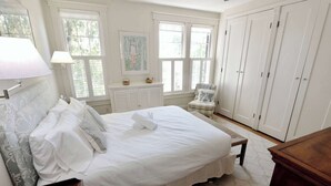 A neatly made bed with pillows, a bedside lamp, a chair, a wardrobe, and a window with shutters. - 'Book Hill' Georgetown House, Walkable with Garage (Washington)