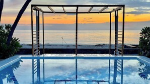 Ein Pool ohne Ende mit Blick auf den Ozean bei Sonnenuntergang.
