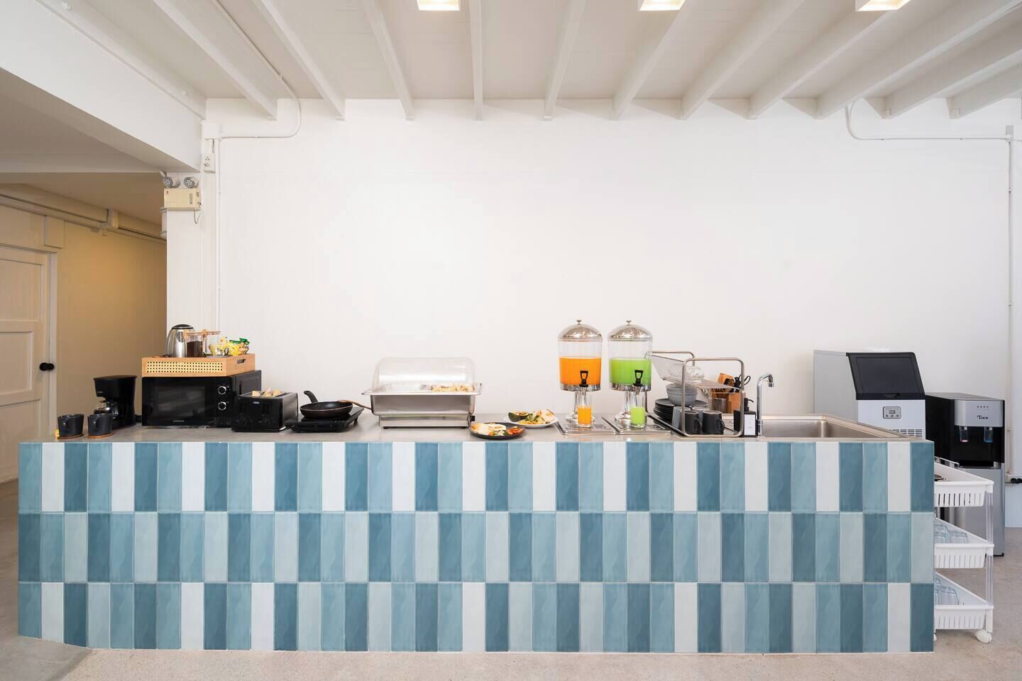 Un espace d’accueil d’hôtel comprenant un comptoir d’enregistrement, une machine à café, un point de vente de nourriture et un distributeur d’eau.