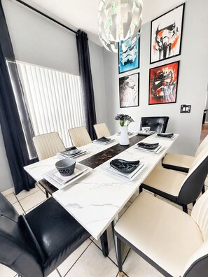 A modern dining area with a long table, chairs, and Star Wars-themed decor. - Star Wars & Wizards Themed XL Pool Home Near Disney (Davenport)