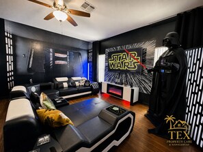 A Star Wars-themed room with a sofa, a Darth Vader statue, and a wall with a Star Wars logo. - Star Wars & Wizards Themed XL Pool Home Near Disney (Davenport)