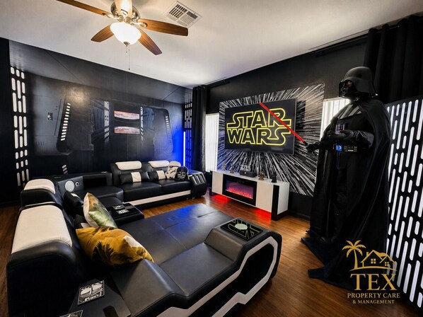 A Star Wars-themed room with a sofa, a ceiling fan, and a Darth Vader statue. - Star Wars & Wizards Themed XL Pool Home Near Disney (Davenport)
