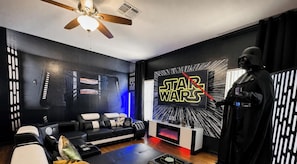 Ein Star Wars-zimmer mit einer Couch, einem Deckenventilator und einer Darth-Vader-Statue.