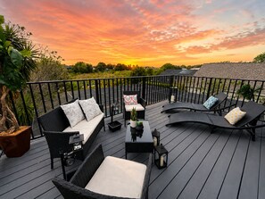 Un terrazzo con mobili da esterno, una pianta in vaso e vista sul tramonto.