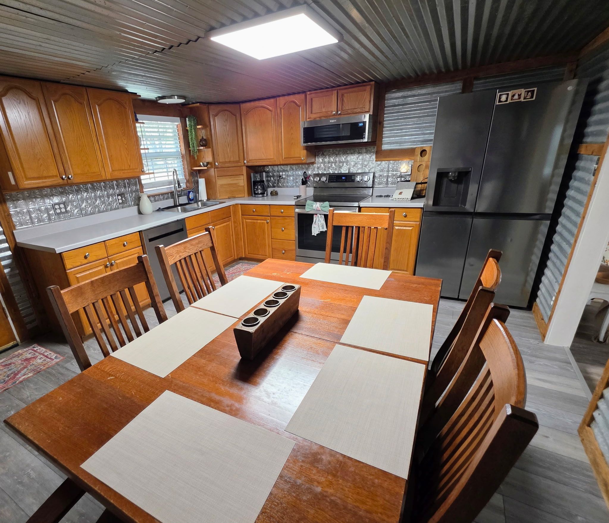 A compact kitchen with wooden cabinets, a microwave, a stove, and a refrigerator.