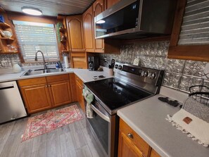 A kitchen with wooden cabinets, a stainless steel stove, a microwave, and a sink.
