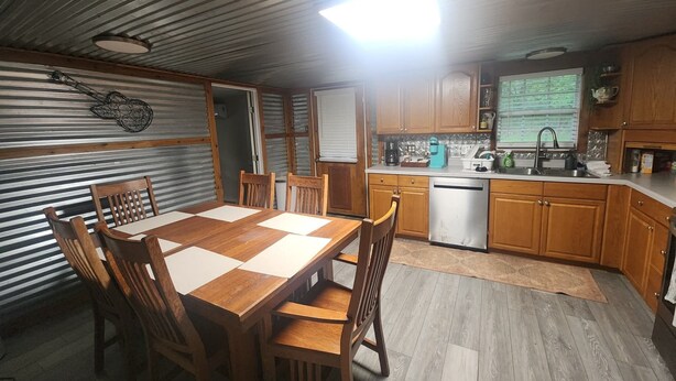Une cuisine compacte avec des meubles en bois, un lave-vaisselle encastré et un coin repas comprenant une table et des chaises en bois.