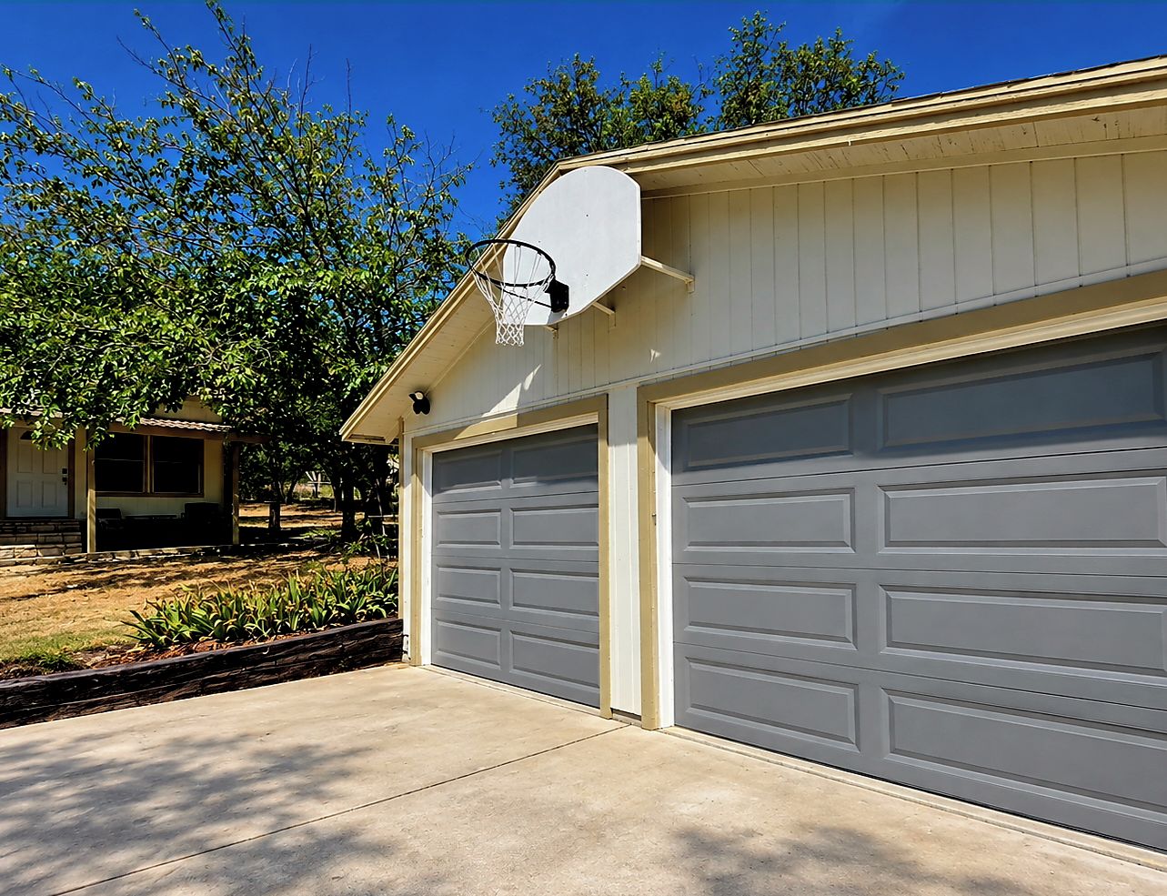 A residential garage with two grey garage doors and a satellite dish on the roof.