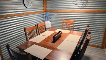Un comedor con una mesa y sillas de madera, un dispensador de agua y un reloj en la pared.