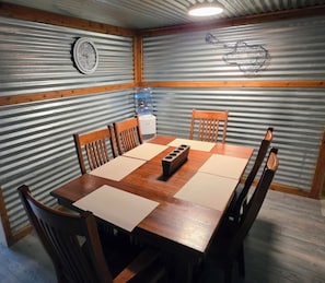 A dining area with a wooden table and chairs, a water dispenser, and a clock on the wall.