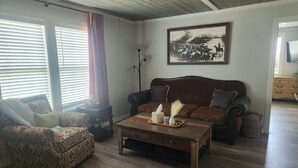 Un salon comprenant un canapé, un fauteuil, une table basse et un tableau accroché au mur.
