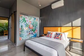 Un dormitorio moderno con una cama grande, un mural llamativo en la pared y vistas al exterior.