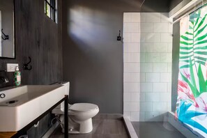 Un baño moderno con lavamanos, inodoro y ducha blancos.