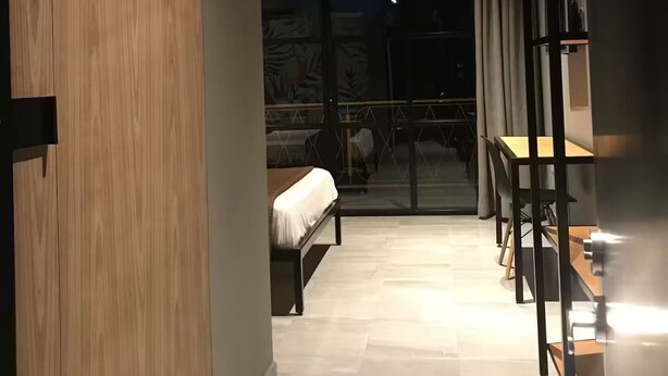 A modern hotel room with a wooden wardrobe, a bed, a dining table, and a balcony with a view. - A&R Luxury Suite (San José del Cabo)