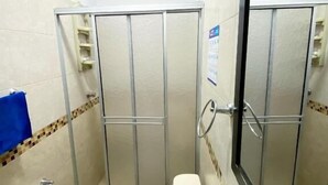 A small bathroom with a toilet, sink, and shower stall.