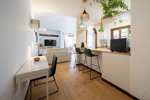 Eine moderne Küche mit Essbereich, Holzboden und Fernseher.