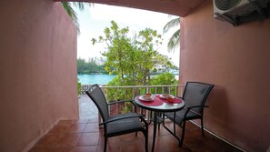 A balcony with a table and chairs, overlooking a body of water and greenery.