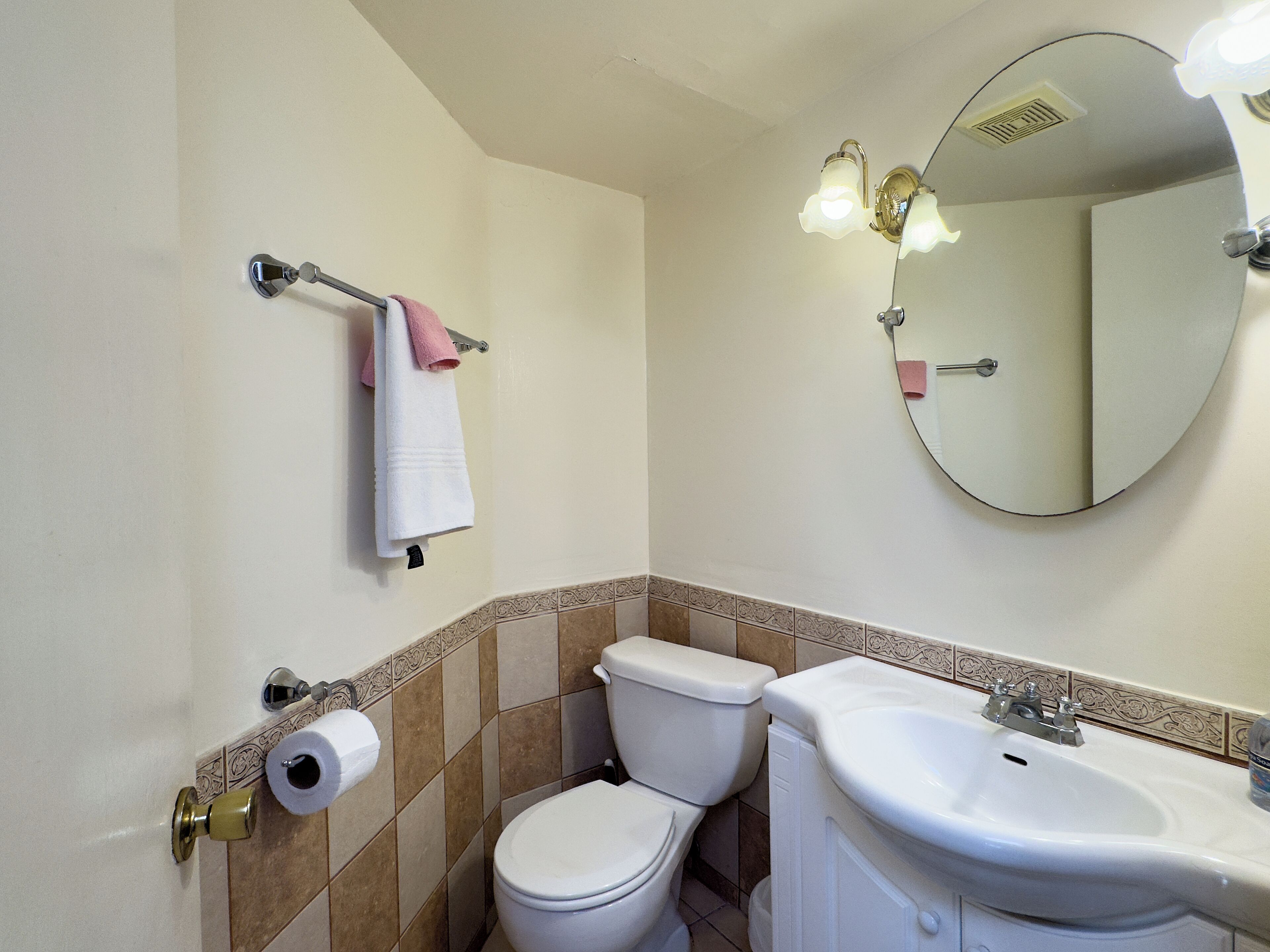 A bathroom with a toilet, sink, and a towel rack with a pink towel.