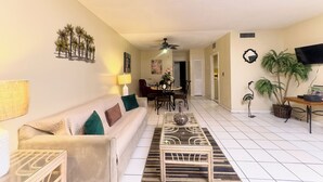 A living room with a sofa, coffee table, and a dining area with chairs and a table.