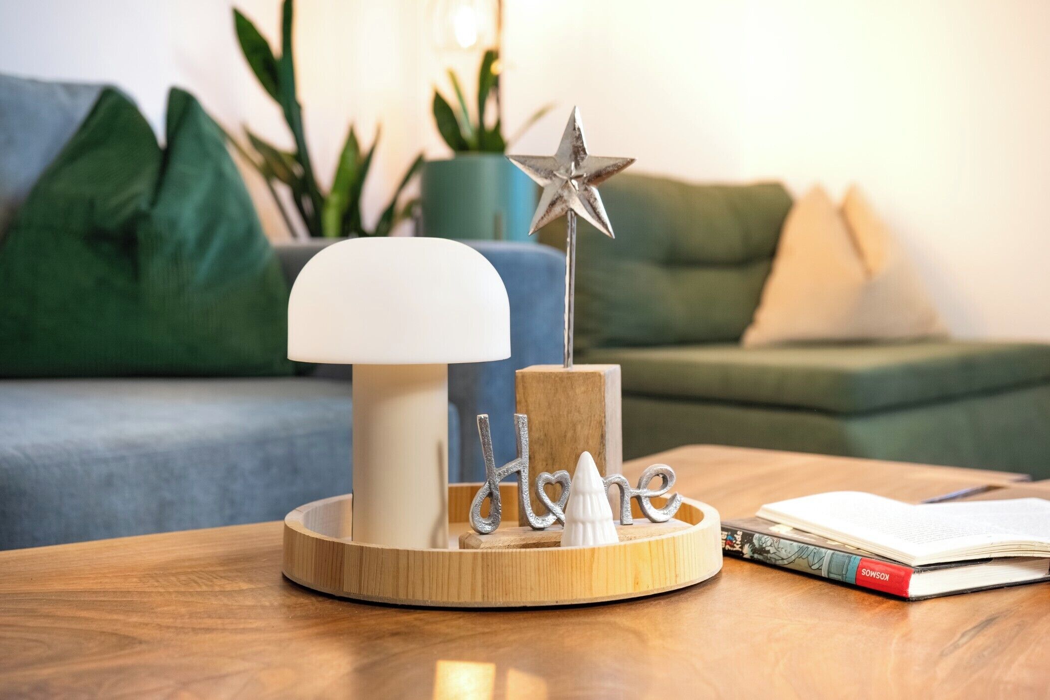 A wooden table with a white lamp, a decorative star, and the word 'home' on a wooden stand.
