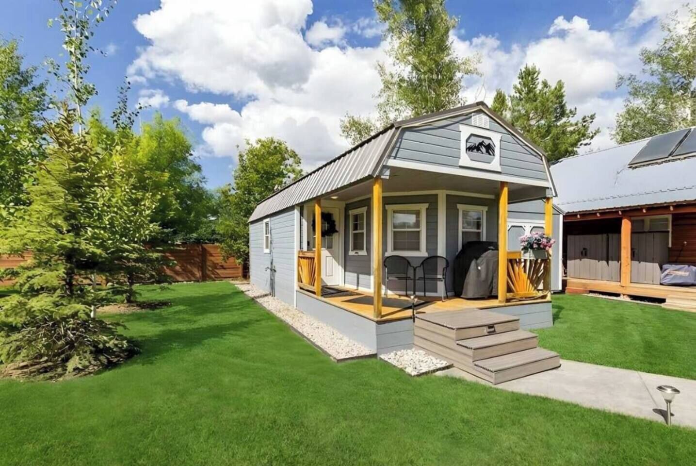 A small, single-story house with a porch, a grill, and a covered outdoor seating area.