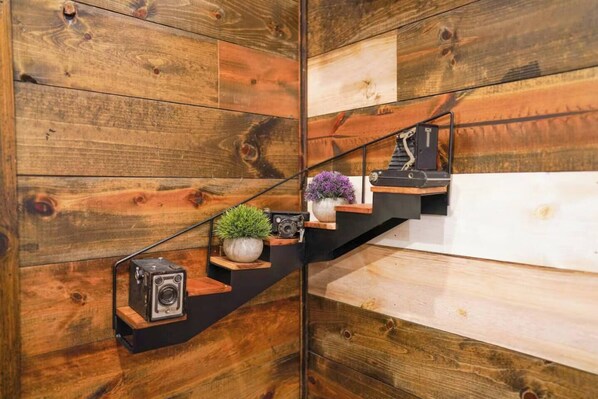 A wooden staircase with a minimalist design, featuring a camera and a potted plant on the steps.