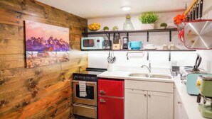 Une cuisine avec des murs en bois, un four à micro-ondes, un évier et un meuble rouge.