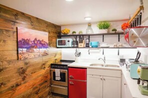 A kitchen with wooden walls, a microwave, a sink, and a red cabinet.