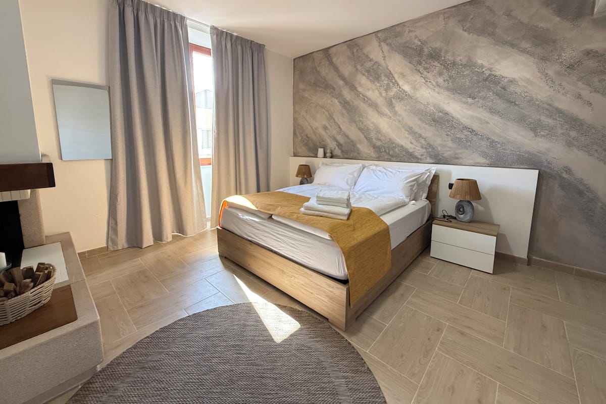 A bedroom with a bed, nightstand, lamp, and a large abstract wall mural.