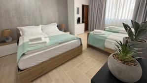 Et moderne hotelværelse med to senge, et stort vindue med gardiner, en potteplante og trægulv.