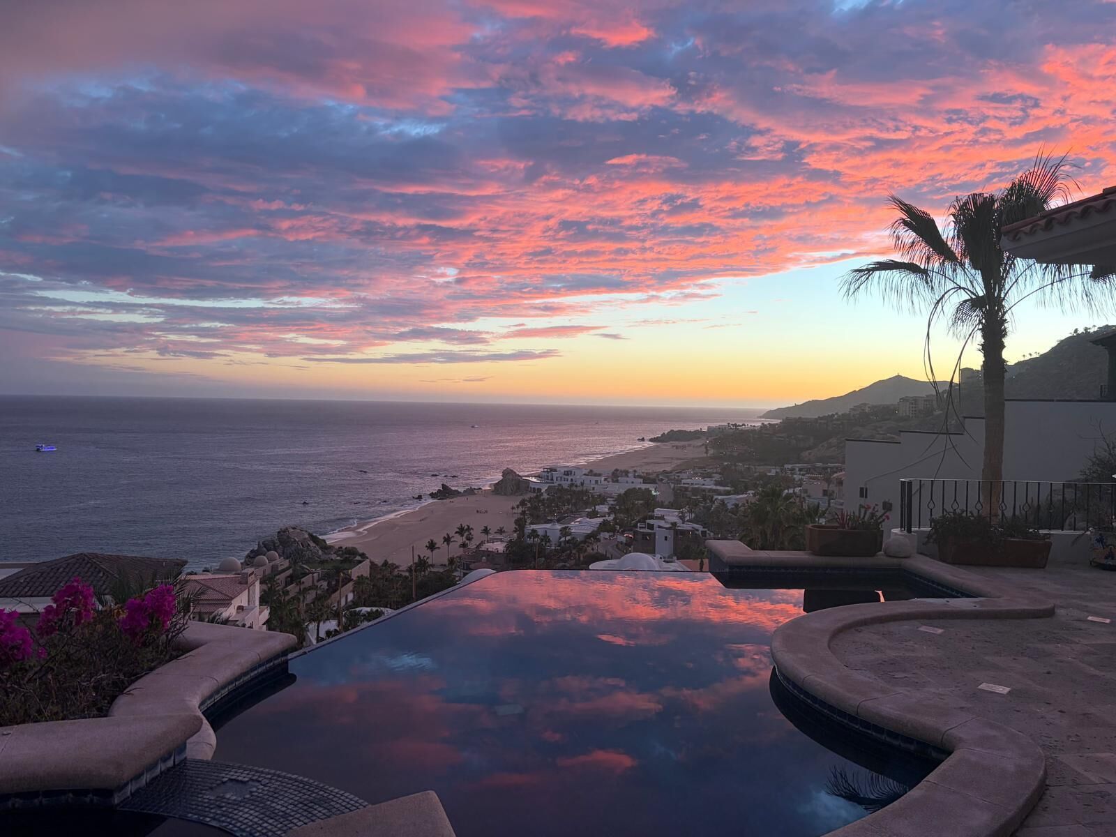 A pool with a view of the ocean and a sunset.