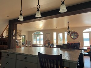 A kitchen with a large island, wooden beams, and pendant lighting.