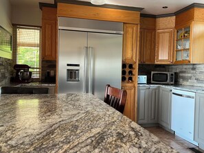 A kitchen with a granite countertop, stainless steel appliances, wooden cabinets, and a built-in wine rack.