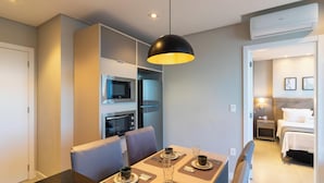 Quarto de hotel moderno com área de jantar, cozinha compacta e quarto separado.