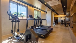 Uma academia com esteiras, elípticos e equipamentos de ginástica.