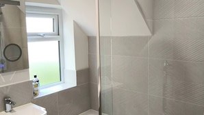 Un baño moderno con ducha, lavamanos y ventana.
