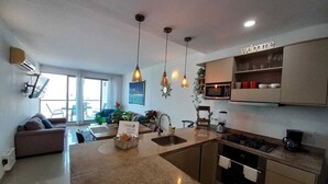 Eine moderne Küche mit Kochinsel, ein Essbereich mit einer Couch und ein Wohnzimmer mit Fernseher.