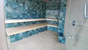 Ein Badezimmer mit Dusche, gefliesten Wänden und einer Sitzbank.
